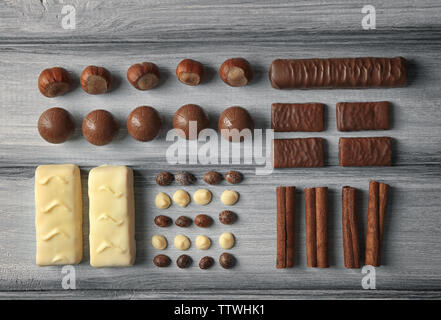 Schokolade und Nüsse auf grauem Hintergrund Holz, Ansicht von oben Stockfoto