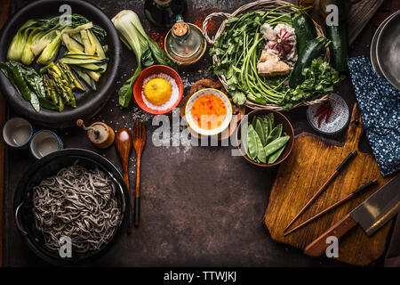 Asiatische Lebensmittel Hintergrund. Leckere vegetarische Zutaten. Verschiedene grüne Gemüse, Soba Nudeln - buchweizen Nudeln, Geschmack Salz und Chili Hot Sauce auf r Stockfoto