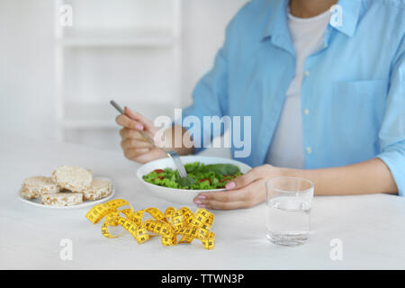 Frau Salat und Maßband auf Tisch Stockfoto