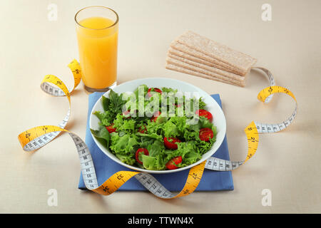 Frischer Salat und Maßband am weißen Tisch Stockfoto