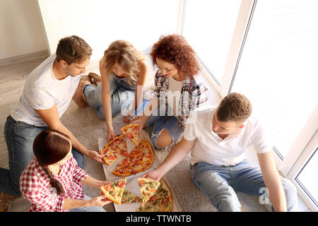 Freunde Spaß haben und essen Pizza beim Sitzen auf dem Boden Stockfoto