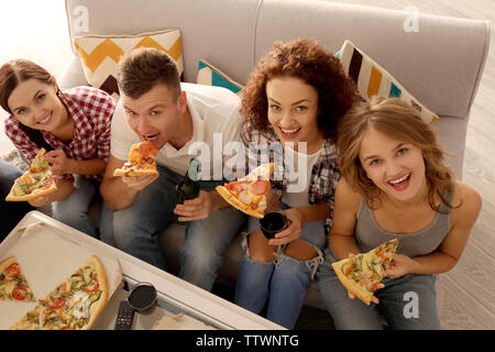 Freunde sitzen auf der Couch und Essen lecker Pizza Stockfoto