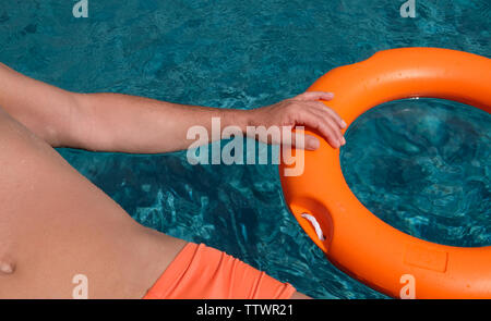 Mann Schwimmen im Schwimmbad an einem Rettungsring Stockfoto