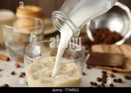 Gießen Milch in ein Glas auf dem Tisch, Nahaufnahme Stockfoto