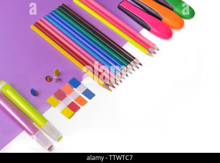 Bunte Bleistifte und Kugelschreiber neon auf mauve Papier und weissem Hintergrund Stockfoto