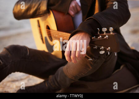 Stattlicher Mann mit Gitarre am Strand Stockfoto