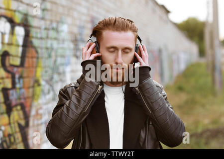 Schöner Mann in Kopfhörer Musik hören im Freien Stockfoto