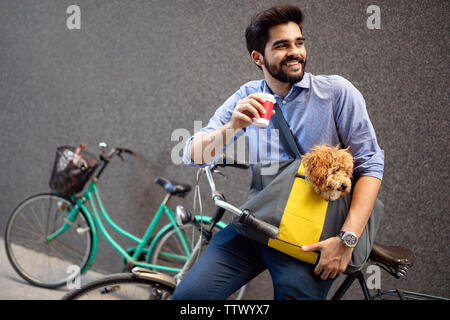 Schön lächelnden Mann sitzt auf einem Fahrrad auf der Straße und trinken Kaffee. Stockfoto