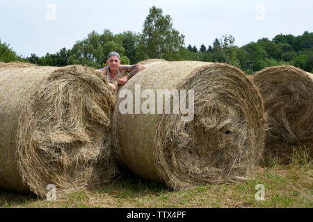 Mann stand unter runde Heuballen und genießen die heißen Sommer Sonne in einem ländlichen Gebiet von Zala Ungarn Stockfoto