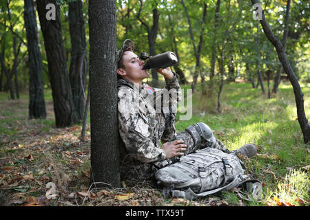 Soldat Trinkwasser aus Kantine in Wald Stockfoto