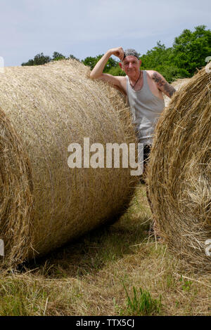 Mann stand unter runde Heuballen und genießen die heißen Sommer Sonne in einem ländlichen Gebiet von Zala Ungarn Stockfoto