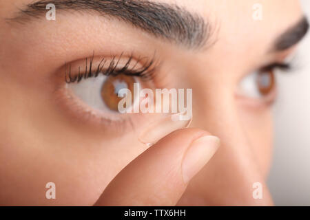 Junge Frau die Kontaktlinsen in den Augen, die Ansicht zu schließen. Medizin und Vision Concept Stockfoto