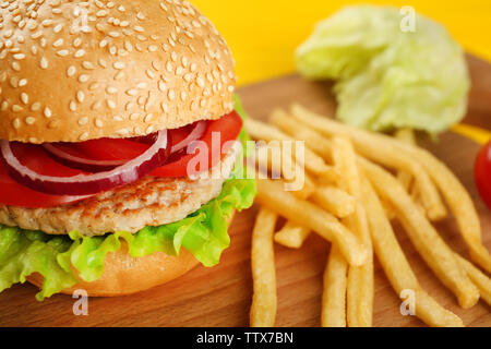 Leckere Burger, kleine USA-Flagge und Chips auf Schneidebrett Stockfoto