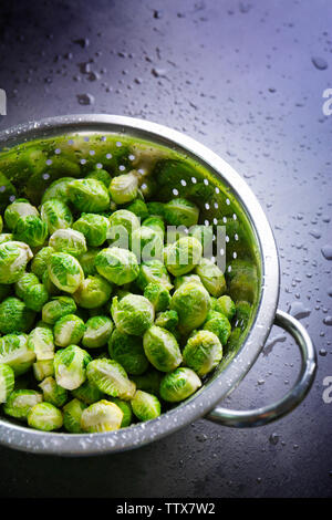 Rosenkohl in Sieb auf Tisch Stockfoto