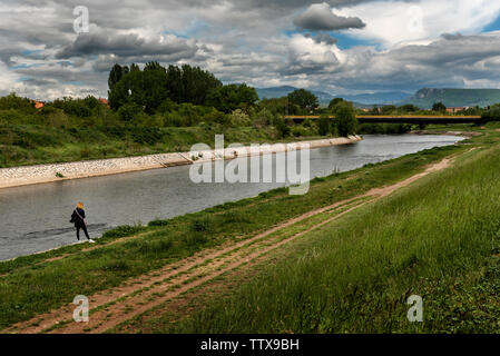 Junge blonde Frau, warten, dass jemand an einem Flussufer Stockfoto