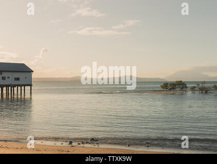 Historische Port Douglas Zucker Wharf auf Stelzen über das ruhige Meer im tropischen Queensland, mit fernen Hügel und eine schöne Dämmerung Himmel Stockfoto