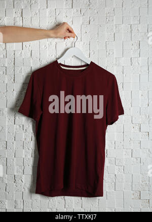 Leere maroon-t-shirt gegen Licht strukturierten Hintergrund Stockfoto