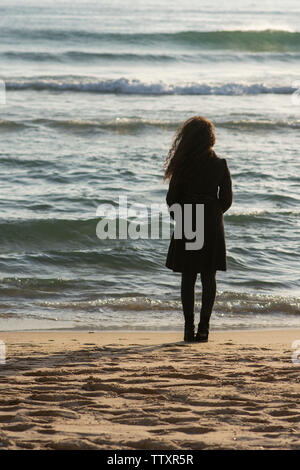 Rückansicht der jungen Frau, die am Strand Stockfoto