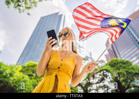 Travel und Technologie. Junge Frau Tourist mit der Flagge von Malaysia ist ein Stadtplan in einem Smartphone für die Navigation Stockfoto