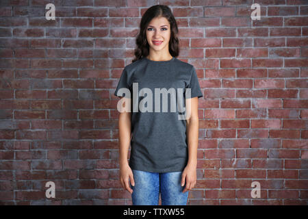Junge Frau in leeren grauen T-Shirt stehend gegen Mauer Stockfoto