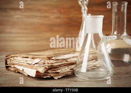 Glaskolben und altes Buch auf Holztisch, Nahaufnahme Stockfoto
