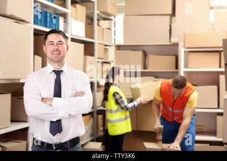 Junge Arbeitnehmer mit Boxen im Lager Stockfoto