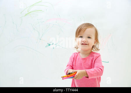 Süße kleine Mädchen Zeichnung an der Wand Stockfoto