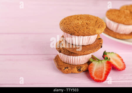 Eis cookie Sandwiches mit frischen Erdbeeren auf rosa Holz- Hintergrund Stockfoto