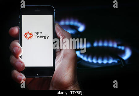 Ein Mann auf der Website Logo auf der Suche nach Energie Firma PFP-Energie auf seinem Mobiltelefon vor seinem Gaskocher (Editorial nur verwenden) Stockfoto
