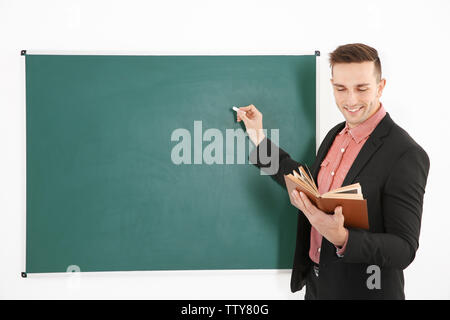 Junge männliche Lehrer neben Tafel auf der weissen Tafel Stockfoto