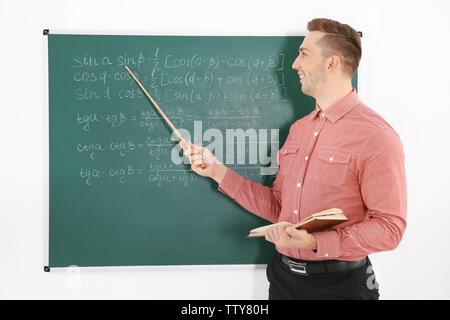 Junge männliche Lehrer neben Tafel auf der weissen Tafel Stockfoto