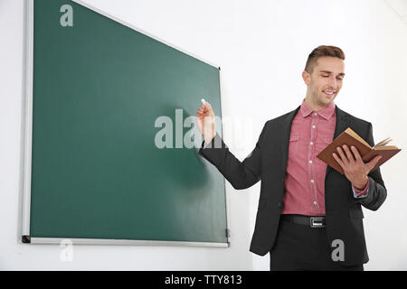 Junge männliche Lehrer neben Tafel auf der weissen Tafel Stockfoto
