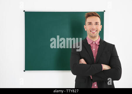 Junge männliche Lehrer neben Tafel auf der weissen Tafel Stockfoto