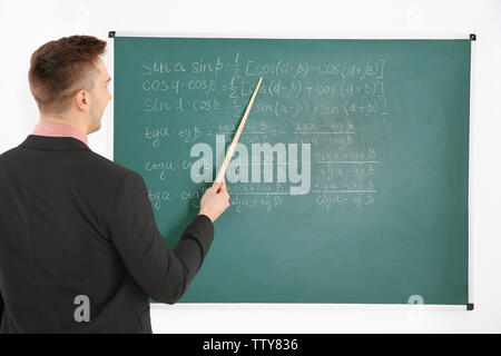 Junge männliche Lehrer neben Tafel auf der weissen Tafel Stockfoto