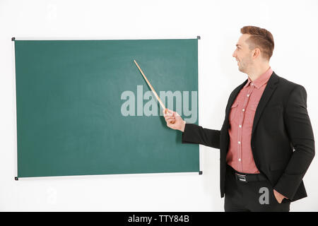 Junge männliche Lehrer neben Tafel auf der weissen Tafel Stockfoto