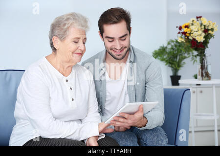 Großmutter und Enkel mit Tablet-PC auf dem Sofa zu Hause Stockfoto