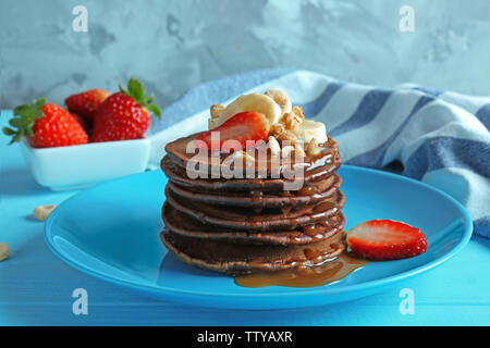 Blaue Platte mit köstlichen Schokolade Pfannkuchen mit Erdbeere und Banane auf hölzernen Tisch dekoriert Stockfoto
