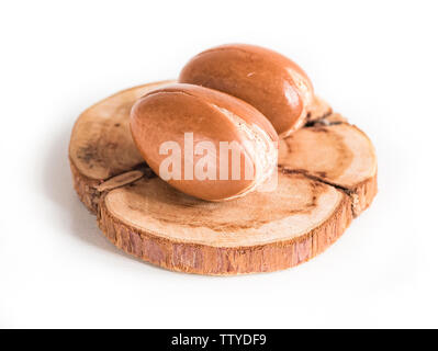 Marokkanische Arganöl Muttern auf Holz Hintergrund close-up Weiß isoliert. Argania spinosa Samen. Stockfoto