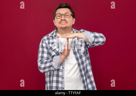 Ich brauche mehr Zeit, bitte. Portrait von sorgen im mittleren Alter Geschäftsmann in lässig-kariertem Hemd und Brille mit Time out Geste, pleadi Stockfoto