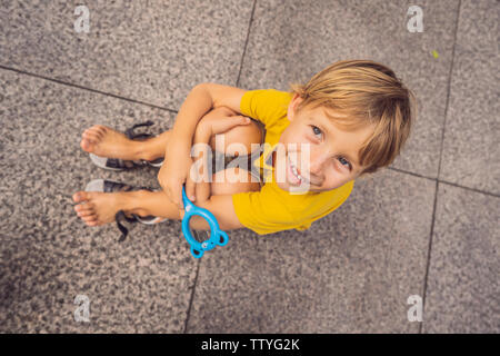 Junge sitzt auf dem Boden und schaut in eine Lupe Stockfoto