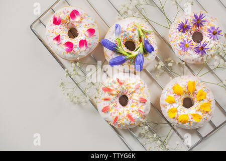 Delicious Doughnuts und Blumen auf backaufsatz und hellen Hintergrund Stockfoto