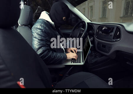 Auto Dieb hacking Security Systems mit Laptop Stockfoto