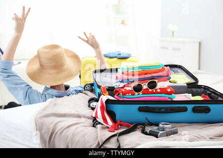 Geöffnet traveler Case mit Kleidung und glückliche Frau auf Hintergrund Stockfoto