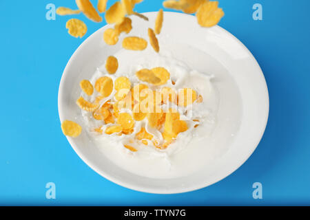 Cornflakes mit Milch in der Schüssel auf blauem Hintergrund Stockfoto