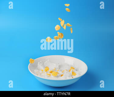 Cornflakes mit Milch in der Schüssel auf blauem Hintergrund Stockfoto