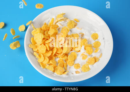 Cornflakes mit Milch in der Schüssel auf blauem Hintergrund Stockfoto