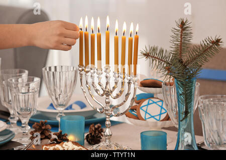 Weibliche hand Anwendung am Tisch serviert für Chanukka zu menorah Stockfoto