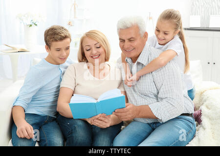 Senior Paar lesen Buch zu Enkelkindern beim Sitzen auf einem Sofa im Wohnzimmer. Stockfoto