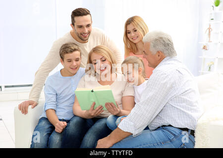 Happy Family lesen Buch beim Sitzen auf einem Sofa im Wohnzimmer. Stockfoto
