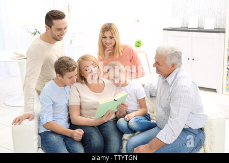 Happy Family lesen Buch beim Sitzen auf einem Sofa im Wohnzimmer. Stockfoto